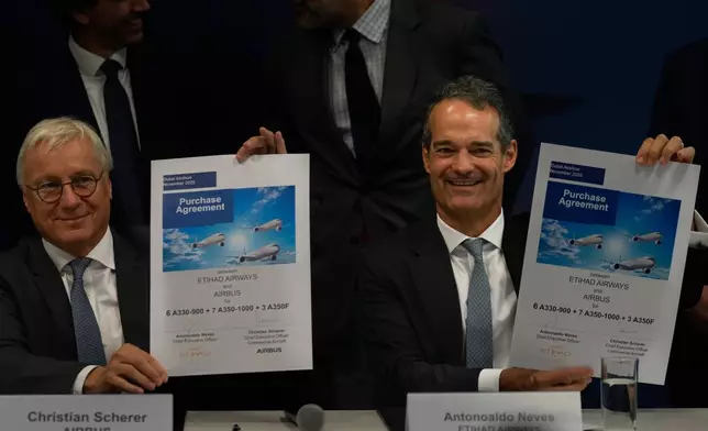 Airbus' CEO of commercial aircraft Christian Scherer, left and Etihad Airways CEO Antonoaldo Neves show purchase agreement at a press conference after announcing a deal to purchase 16 Airbus planes at the Dubai Air Show, United Arab Emirates, Tuesday, Nov. 18, 2025. (AP Photo/Altaf Qadri)