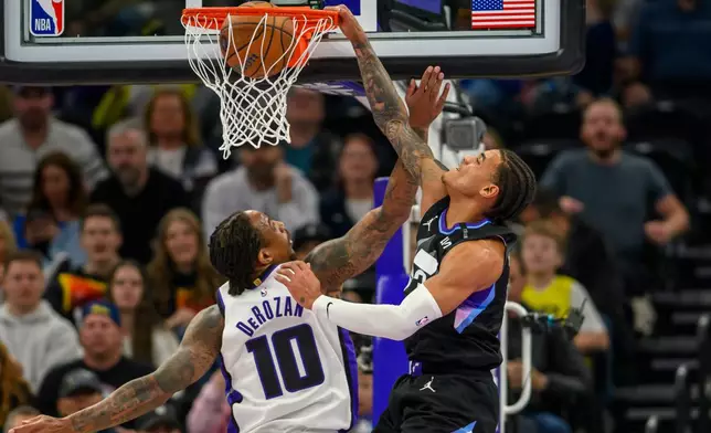 Utah Jazz guard Keyonte George, right, dunks the ball over Sacramento Kings guard DeMar DeRozan, left, during the first half of an NBA Cup basketball game Friday, Nov. 28, 2025, in Salt Lake City. (AP Photo/Tyler Tate)