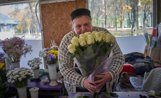 Florist Olha Komanytska, an owner of a small flower kiosk, wraps a rose bouquet in the frontline city of Kherson, Southern Ukraine, Nov. 2, 2025. (AP Photo/Efrem Lukatsky)