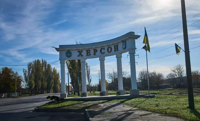 A sign reading "Kherson" by the national flag is seen on the deserted road to the frontline city in Kherson, Southern Ukraine, Nov. 2, 2025. (AP Photo/Efrem Lukatsky)