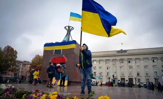 FILE- In this photo taken Sunday, Nov. 13, 2022, a boy waves the national flag as the Ukrainian army liberated the city from the Russian troops in Kherson, Ukraine, Nov. 13, 2022. (AP Photo/Efrem Lukatsky, File)