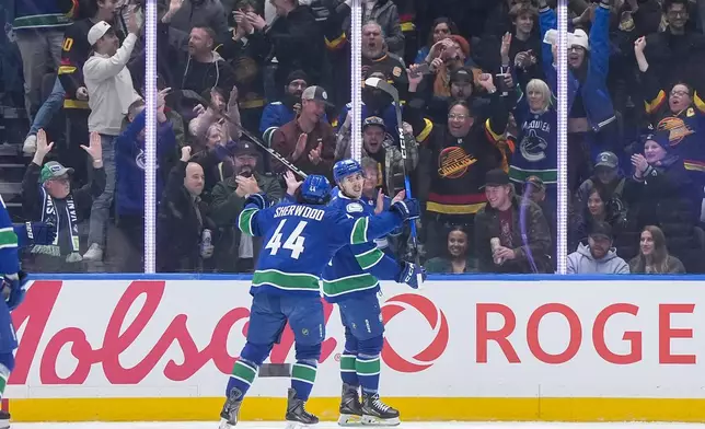 Vancouver Canucks' Linus Karlsson, back right, celebrates his goal with teammate Kiefer Sherwood during the first period of an NHL hockey game against the Colorado Avalanche, in Vancouver, B.C., Sunday, Nov. 9, 2025. (Darryl Dyck/The Canadian Press via AP)
