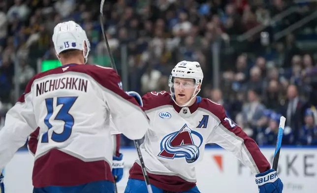 Colorado Avalanche's Nathan MacKinnon (29) celebrates his second goal against the Vancouver Canucks with teammate Valeri Nichushkin during the first period of an NHL hockey game, in Vancouver, B.C., Sunday, Nov. 9, 2025. (Darryl Dyck/The Canadian Press via AP)