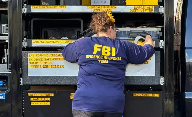 An FBI agent stands by an Evidence Response Team truck outside a home in a Dearborn, Mich., neighborhood on Friday, Oct. 31, 2025. (AP Photo/Mike Householder)