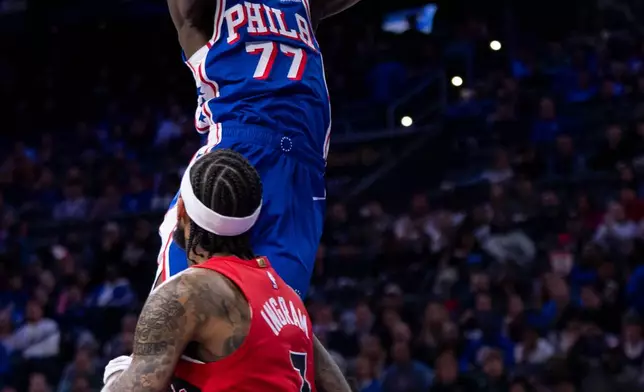 Philadelphia 76ers' VJ Edgecombe, top, dunks the ball with Toronto Raptors' Brandon Ingram, bottom, defending during the first half of an NBA basketball game, Wednesday, Nov. 19, 2025, in Philadelphia. (AP Photo/Chris Szagola)