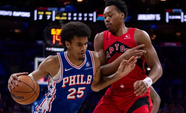 Philadelphia 76ers' Dom Barlow, left, drives to the basket against Toronto Raptors' Scottie Barnes during the first half of an NBA basketball game, Wednesday, Nov. 19, 2025, in Philadelphia. (AP Photo/Chris Szagola)