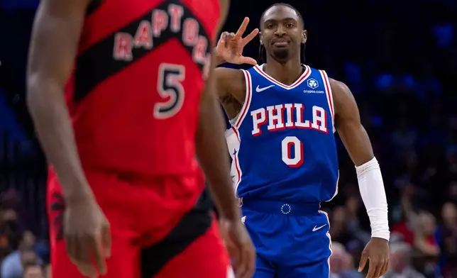 Philadelphia 76ers' Tyrese Maxey, right, reacts to his three-point shot over Toronto Raptors' Immanuel Quickley, left, during the first half of an NBA basketball game, Wednesday, Nov. 19, 2025, in Philadelphia. (AP Photo/Chris Szagola)