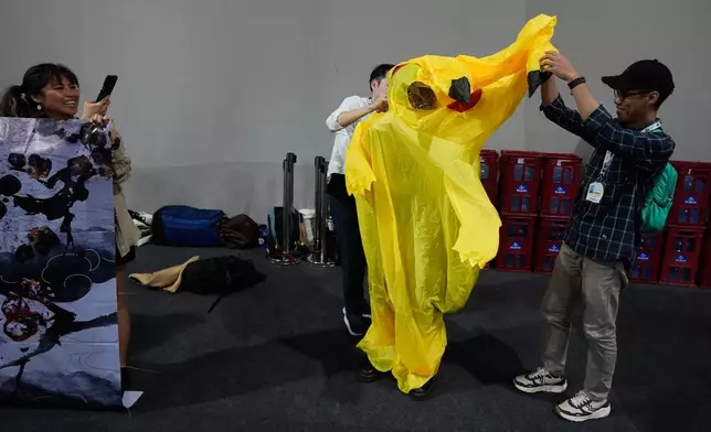 Activists, one trying to put on a Pikachu costume, protest Japan's financing of coal and natural gas projects during the COP30 U.N. Climate Summit, Friday, Nov. 14, 2025, in Belem, Brazil. (AP Photo/Fernando Llano)
