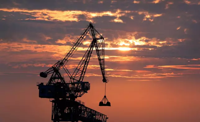 FILE - A crane is silhouetted as it transfers coal during a sunset at a port in Osaka, western Japan on Aug. 18, 2019. (AP Photo/Andy Wong, File)