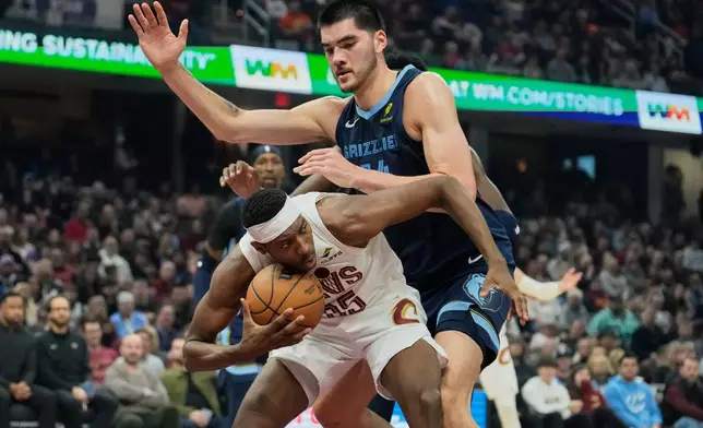 Cleveland Cavaliers forward Nae'Qwan Tomlin, bottom, is fouled by Memphis Grizzlies center Zach Edey, top, in the first half of an NBA basketball game Saturday, Nov. 15, 2025, in Cleveland. (AP Photo/Sue Ogrocki)