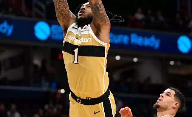 Washington Wizards forward Cam Whitmore (1) dunks over Brooklyn Nets forward Michael Porter Jr. during the first half of an NBA basketball game, Sunday, Nov. 16, 2025, in Washington. (AP Photo/John McDonnell)
