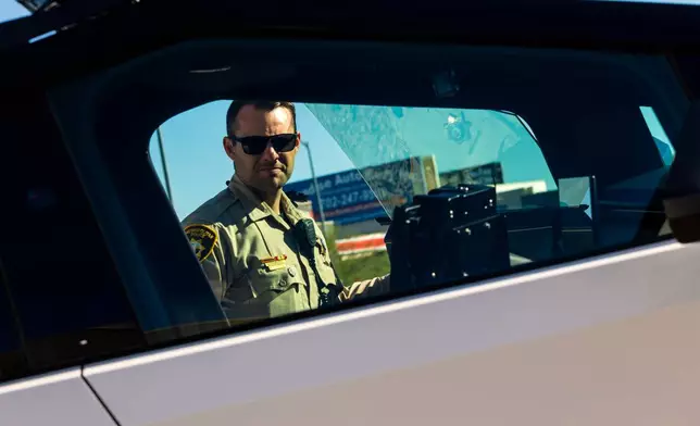A member of the Las Vegas Police Department inspects a Tesla Cybertruck, part of the department's fleet of vehicles, in Las Vegas on Tuesday Oct, 28th 2025. (AP Photo/Ty ONeil)