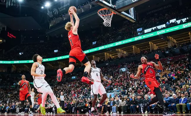 Toronto Raptors' Gradey Dick (1) dunks against the Brooklyn Nets as teammate Scottie Barnes (4) reacts during first half NBA basketball action in Toronto, on Sunday, Nov. 23, 2025. (Sammy Kogan/The Canadian Press via AP)