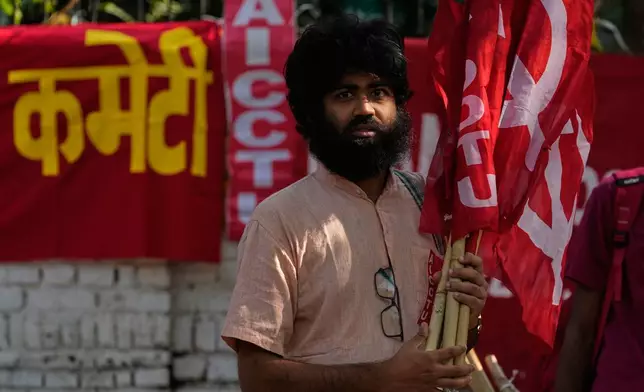 An activist of a trade union carries flags for distribution to fellow activist during a protest against the government's rollout of new labor codes in New Delhi, India, Wednesday, Nov. 26, 2025. (AP Photo/Manish Swarup)