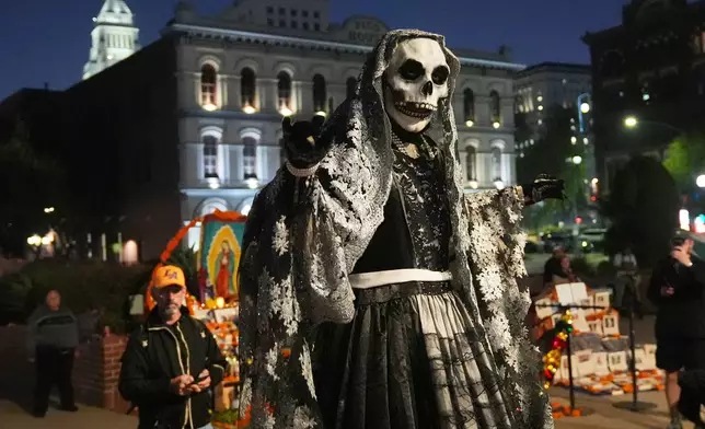A members of Teatro del Pueblo dressed as La Catrina performs "La Danza de la Muerte" play, part of the Day of the Dead celebrations at Olvera Street, Sunday, Oct. 26, 2025, in Los Angeles. (AP Photo/Damian Dovarganes)