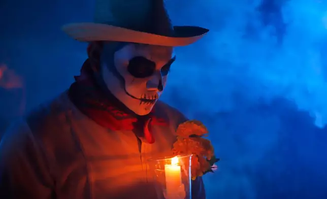 A man with skull make up holds a candle during the Paseo de las Animas parade as part of the Day of the Dead celebrations in Merida, Mexico, Friday, Oct. 31, 2025. (AP Photo/Martin Zetina)