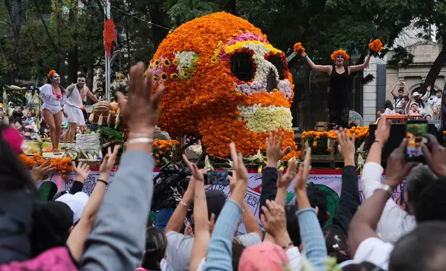 Spectators cheer as they watch the annual Day of the Dead parade in Mexico City, Saturday, Nov. 1, 2025. (AP Photo/Claudia Rosel)