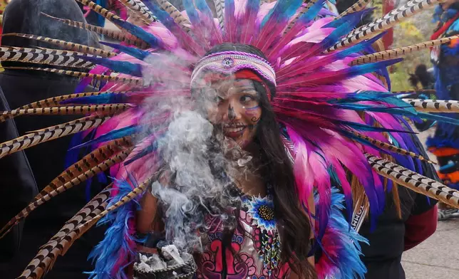 A member of an Aztec dance group holds incense during a commemoration of Día de Muertos (Day of the Dead) at El Colegio High School in Minneapolis on Saturday, Nov. 1, 2025. (AP Photo/Giovanna Dell'Orto)