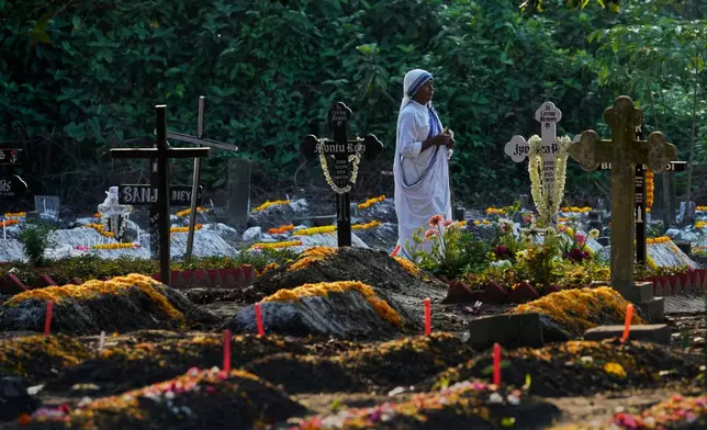 A nun of the Missionaries of Charity, the order founded by Saint Teresa, walks by the graves of their loved ones on All Souls' Day, in Kolkata, India, Sunday, Nov. 2, 2025. (AP Photo/Bikas Das)