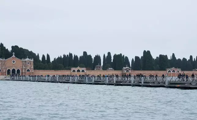 Mourners walk on the 'Votif' Bridge, a 407m temporary floating bridge connecting the city to the cemetery on the island of San Michele, to pay respects to their dead on All Soul's Day, in Venice, Italy, Sunday, Nov. 2, 2025. (AP Photo/Luca Bruno)