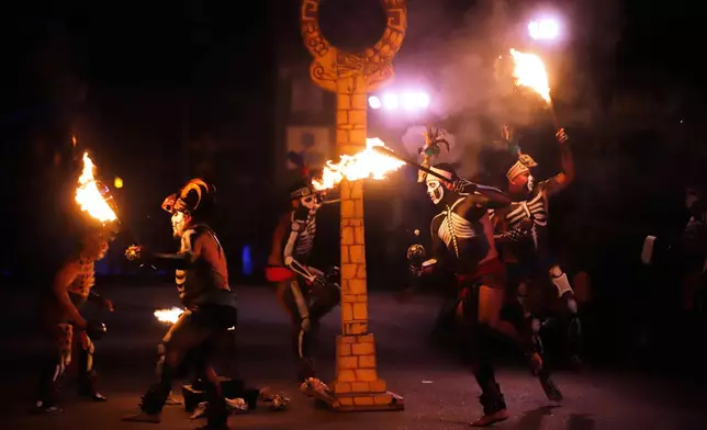 Artists perform as a player of "pelota Maya" during the Paseo de las Animas parade as part of the Day of the Dead celebrations in Merida, Mexico, Friday, Oct. 31, 2025. (AP Photo/Martin Zetina)