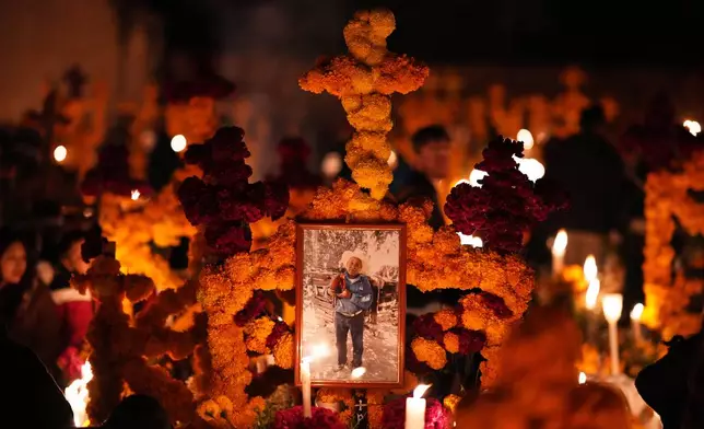 A grave is decorated with cempasuchil flowers and candles celebrating the Day of the Dead at the cemetery in Arocutin, Michoacan state, Mexico, Saturday, Nov. 1, 2025. (AP Photo/Eduardo Verdugo)