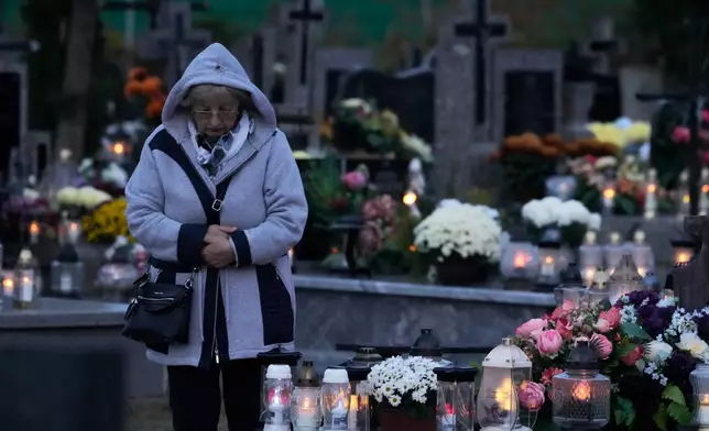 A women observe All Saints' Day, a time for reflecting on those who have died, in Kroczewo near Warsaw, Poland, Saturday, Nov. 1, 2025. (AP Photo/Czarek Sokolowski)