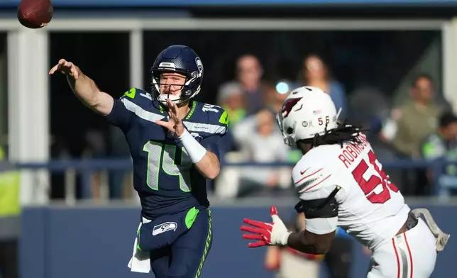 Seattle Seahawks quarterback Sam Darnold (14) throws as he is pressured by Arizona Cardinals defensive end Darius Robinson during the first half of an NFL football game Sunday, Nov. 9, 2025, in Seattle. (AP Photo/Lindsey Wasson)