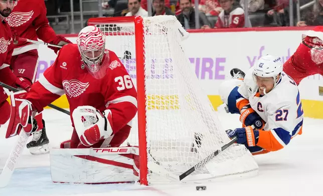 New York Islanders left wing Anders Lee, right, shoots against Detroit Red Wings goaltender John Gibson during the first period of an NHL hockey game Thursday, Nov. 20, 2025, in Detroit. (AP Photo/Ryan Sun)