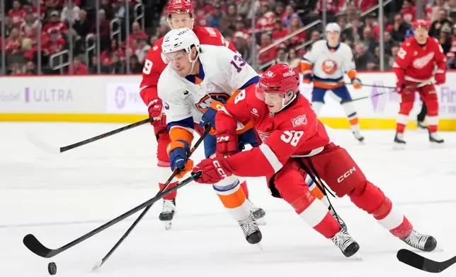 New York Islanders center Mathew Barzal, center, moves the puck against Detroit Red Wings center Nate Danielson, behind, and center Emmitt Finnie during the first period of an NHL hockey game Thursday, Nov. 20, 2025, in Detroit. (AP Photo/Ryan Sun)