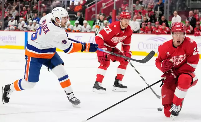 New York Islanders defenseman Ryan Pulock, left, shoots against Detroit Red Wings center Nate Danielson, right, during the first period of an NHL hockey game Thursday, Nov. 20, 2025, in Detroit. (AP Photo/Ryan Sun)