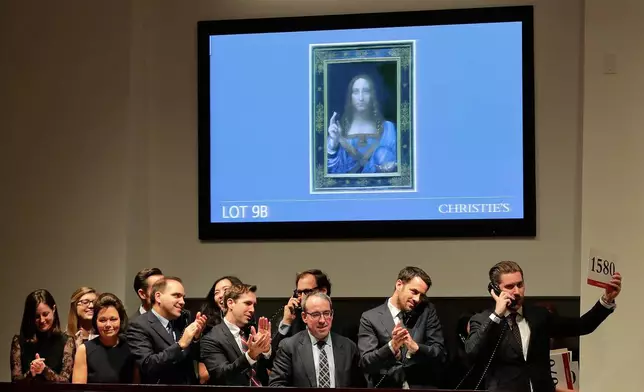 FILE - Bidding representatives react after Leonardo da Vinci's "Salvator Mundi" sold for $450 million at Christie's in New York, Nov. 15, 2017. (AP Photo/Julie Jacobson, File)