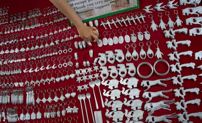 A vendor arranges metal souvenirs made from recycled fragments of unexploded ordnance left from the Vietnam War at a night market in Luang Prabang, Laos, Monday, Nov. 3, 2025. (AP Photo/Eugene Hoshiko)