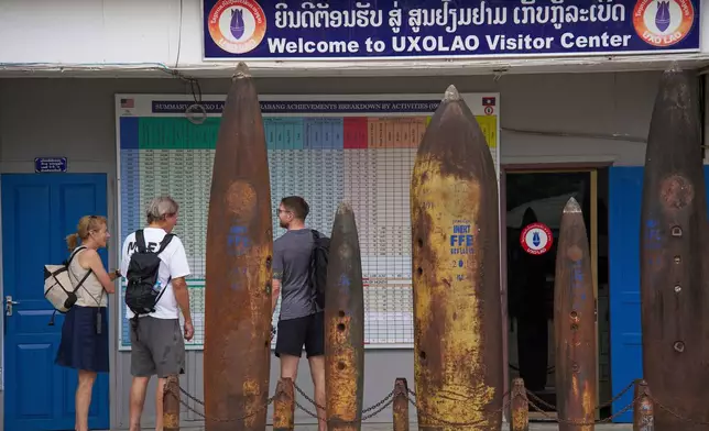 Visitors stand beside remnants of unexploded ordnance recovered during clearance operations at the UXO Lao Visitor Center in Luang Prabang, Laos, Monday, Nov. 3, 2025. (AP Photo/Eugene Hoshiko)