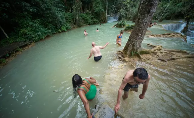 Tourists wade and swim in natural pools at Kuang Si Waterfall, one of the most visited eco-tourism sites near Luang Prabang, Laos, Tuesday, Nov. 4, 2025. (AP Photo/Eugene Hoshiko)