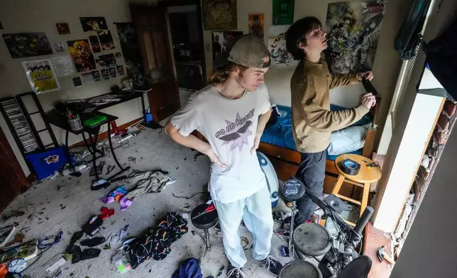 Quinn Ocker, left, and Aidan Bartlow work on installing a tarp over a blown our window in Ocker's bedroom after severe weather hit in the Memorial Northwest subdivision, in Spring, Texas, Monday, Nov. 24, 2025. (Brett Coomer/Houston Chronicle via AP)