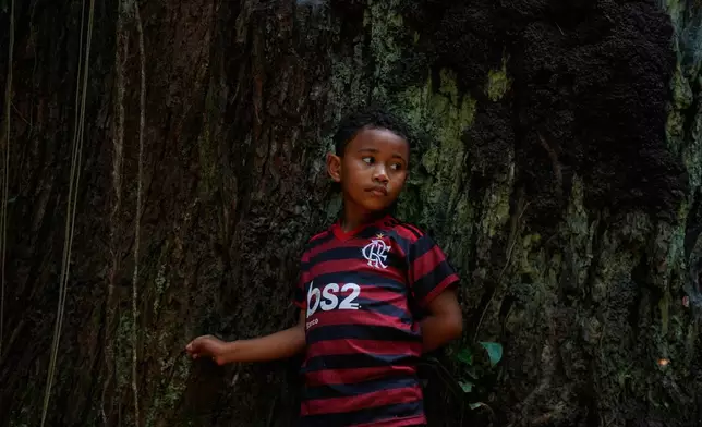 Riquelme listens to his grandpa Edson Coelho during a tour of a quilombola, an Afro-descendant community called Menino Jesus in Acara, Brazil, Tuesday, Nov. 18, 2025. (AP Photo/Fernando Llano)