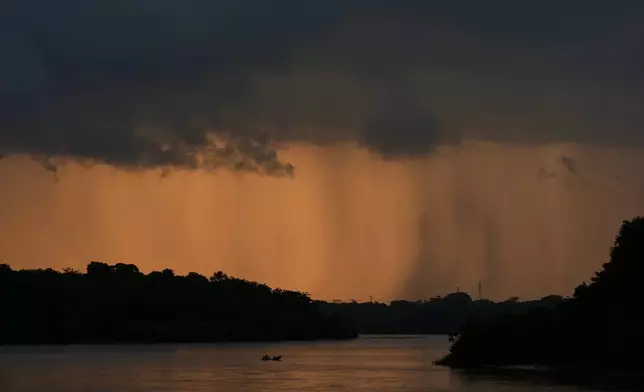 A small boat crosses a river approaching Itacoa Miri, Brazil, Tuesday, Nov. 18, 2025. (AP Photo/Fernando Llano)