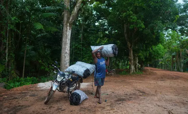 A man carries a charcoal sack to the harbor in Itacoa Miri, Brazil, Tuesday, Nov. 18, 2025, to be sent for sale in Belem. (AP Photo/Fernando Llano)