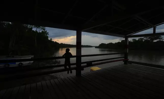 A boy waits for a boat at the harbor in Itacoa Miri, Brazil, Tuesday, Nov. 18, 2025. (AP Photo/Fernando Llano)