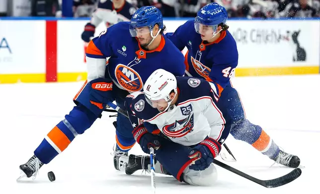 New York Islanders defensemen Alexander Romanov (28) and Matthew Schaefer (48) battle Columbus Blue Jackets left wing Miles Wood (11) for the puck during the third period of an NHL hockey game, Sunday, Nov. 2, 2025, in New York. (AP Photo/Noah K. Murray)
