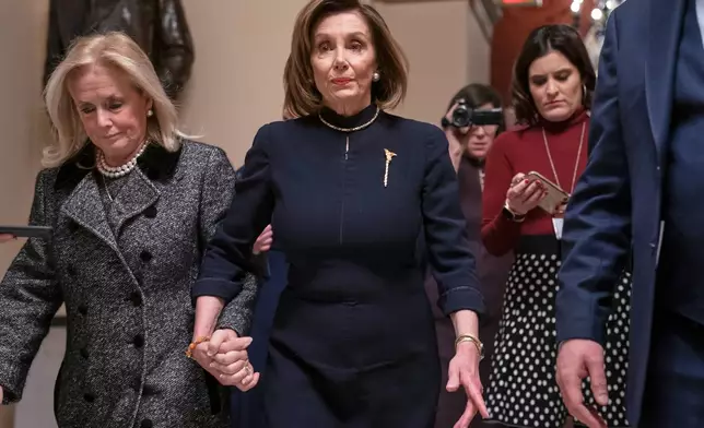 FILE - Speaker of the House Nancy Pelosi, D-Calif., holds hands with Rep. Debbie Dingell, D-Mich., as they walk to the chamber where the Democratic-controlled House of Representatives begins a day of debate on the impeachments charges against President Donald Trump for abuse of power and obstruction of Congress, at the Capitol in Washington, Dec. 18, 2019. (AP Photo/J. Scott Applewhite, File)