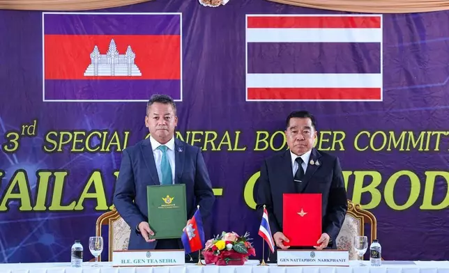 In this photo released by Agence Kampuchea Press (AKP), Cambodian Defense Minister Tea Seiha, left, stands with Thai Defense Minister Natthaphon Narkphanit, right, at the General Border Committee Meeting in Chanthaburi Province, Thailand Saturday, Dec. 27, 2025. (AKP via AP)