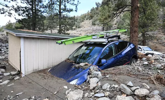 A car is buried in mud after a series of storms Thursday, Dec. 25, 2025, in Wrightwood, Calif. (AP Photo/William Liang)