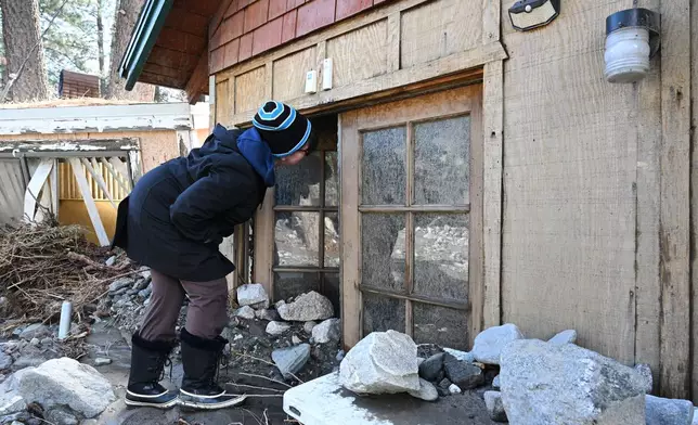 Michelle Meyers inspects her property, buried in mud after a series of storms, Thursday, Dec. 25, 2025, in Wrightwood, Calif. (AP Photo/William Liang)