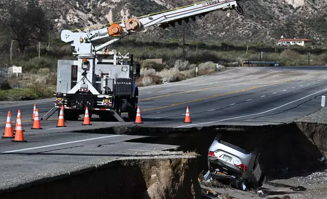 A car is flipped over along a storm-damaged road after a series of storms on Thursday, Dec. 25, 2025, near Phelan, Calif. (AP Photo/William Liang)