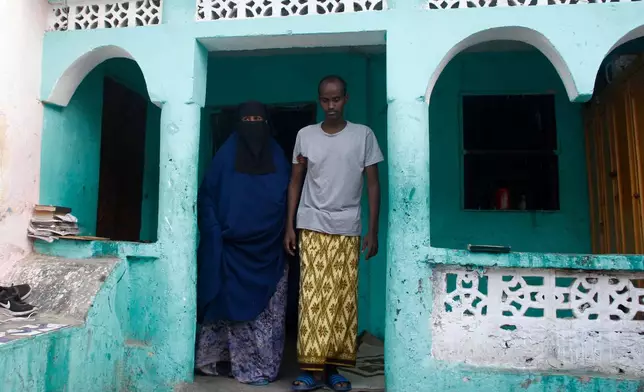 Mohamed Abdi Awale, who says he was tortured by smugglers while trying to reach Europe, is helped by his mother at their home in Mogadishu, Somalia, Monday, Nov. 17, 2025. (AP Photo/Farah Abdi Warsameh)