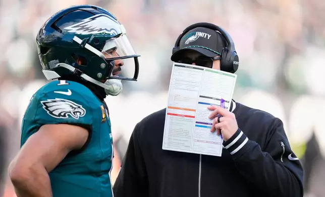 Philadelphia Eagles quarterback Jalen Hurts (1) talks to Eagles' Kevin Patullo during the first half of an NFL football game against the Las Vegas Raiders on Sunday, Dec. 14, 2025, in Philadelphia. (AP Photo/Chris Szagola)