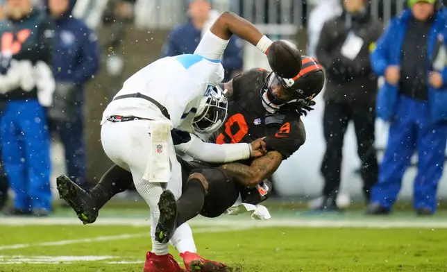 Tennessee Titans quarterback Cam Ward (1) fights off a tackle attempt by Cleveland Browns safety Grant Delpit (9) in the second half of an NFL football game in Cleveland, Sunday, Dec. 7, 2025. (AP Photo/Sue Ogrocki)