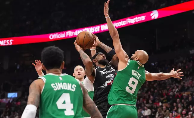Toronto Raptors forward Brandon Ingram, second from right, looks to shoot against Boston Celtics guard Derrick White (9) during first-half NBA basketball game action in Toronto, Sunday Dec. 7, 2025. (Chris Young/The Canadian Press via AP)